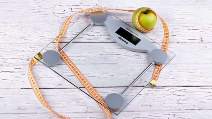 green-apple-orange-tape-measure-lie-on-glass-weighing-scales balança