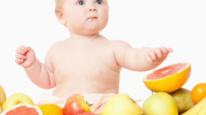 The babe in an environment of the fresh fruit, isolated on the white alimentacao bebe